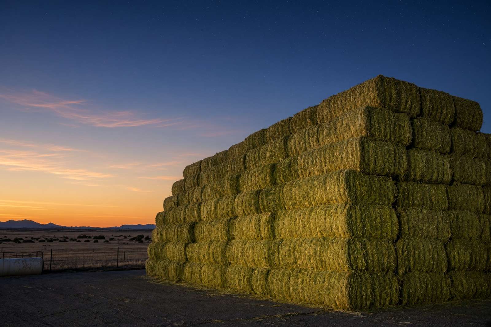 A stack of hay bales at dusk